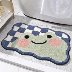 a bathroom rug with a smiling face on the floor in front of a bathtub