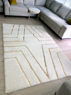 a living room with a large white rug on the floor next to a gray couch