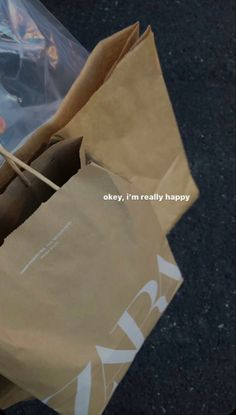 a brown paper bag sitting on top of a black floor next to a cell phone