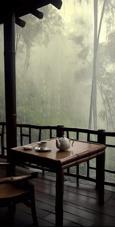 a wooden table sitting on top of a porch next to a forest filled with trees