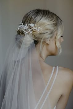 a woman wearing a veil with flowers on it's head and hair comb in her hair