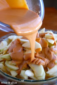 someone pouring caramel sauce on bananas in a glass bowl