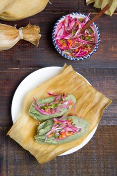 two tacos are sitting on a plate next to some corn