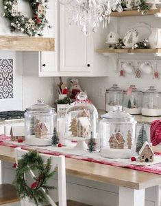 a kitchen with white cabinets and christmas decorations on the counter top, along with glass jars filled with ornaments