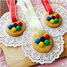 two cookies decorated with candy on top of a doily next to a red ribbon