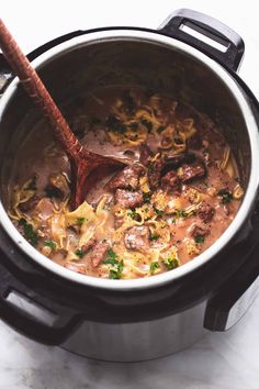 a slow cooker filled with pasta and beef stew, ready to be cooked in the crock pot