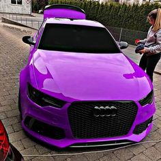 a woman standing next to a purple car