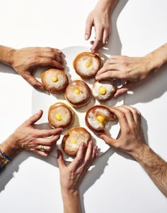 several hands reaching for pastries on a plate