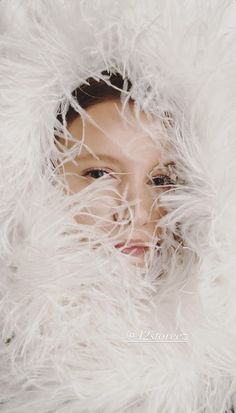 a woman with white fur covering her face and neck, looking out from under the fur