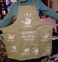 a woman wearing an apron with handprints on it and the words grandma's helping hands