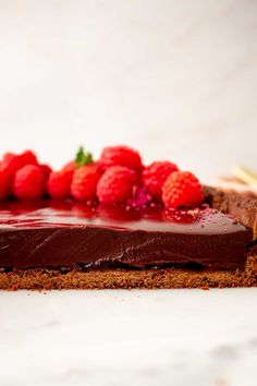 a piece of chocolate cake topped with raspberries on top of a white counter