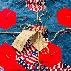 an american flag quilt with red, white and blue stars in the background that has a string tied to it