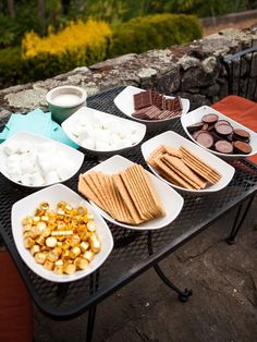 a table topped with plates of food next to a stone wall