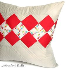 a red and white quilted pillow sitting on top of a table