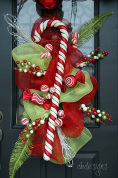 a christmas wreath with candy canes and greenery on the front door for holiday decor