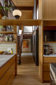 an open kitchen and dining area with wood paneling on the walls, counter tops, and shelves