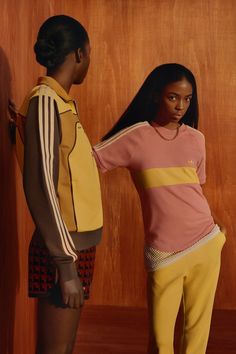 two young women standing next to each other in front of a wooden paneled wall