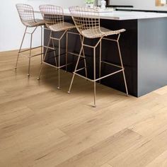 two bar stools sitting next to an island in a kitchen with white walls and wood flooring