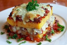 a white plate topped with lasagna casserole covered in sauce and parmesan cheese