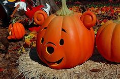 two pumpkins with faces carved into them sitting on hay in front of other pumpkins