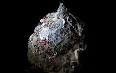 a rock covered in lots of different types of rocks and gravel on a black background