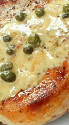 a piece of meat covered in cheese and green olives