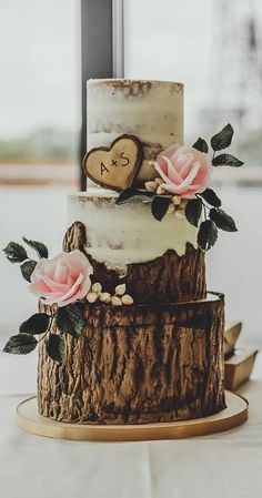 a three tiered wedding cake with pink flowers on the top and initials on the side