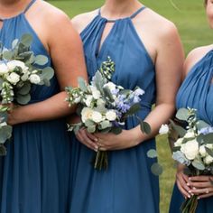 four bridesmaids in blue dresses holding bouquets