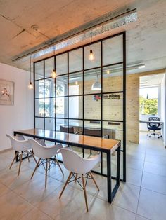 a dining room table with white chairs and an open glass wall in the background,