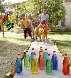 several children are playing with water bottles on a table in front of a house that is decorated with balloons and streamers