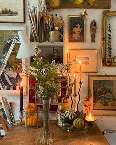 a wooden table topped with a vase filled with flowers next to candles and pictures on the wall