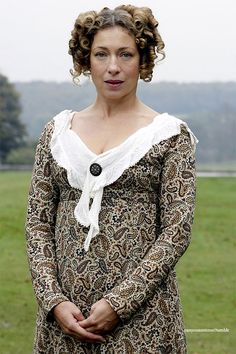 a woman standing in front of a field wearing a brown and white dress with ruffled collar