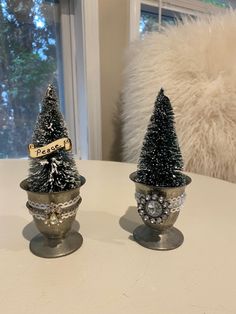 two small christmas trees sitting on top of a table