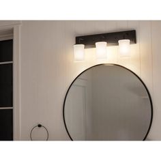 a bathroom with a round mirror and two lights on the wall next to a door