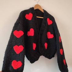 a black sweater with red hearts on it