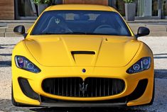 a yellow sports car parked in front of a building