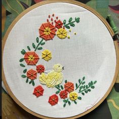 an embroidery project with flowers and a bird in the center on a white cloth background