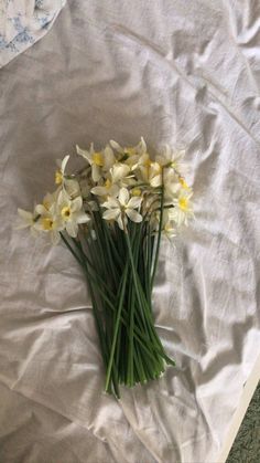 a bunch of white and yellow flowers laying on top of a sheeted bed spread