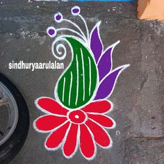 a colorful flower painted on the ground next to a car tire and sign that says sindhhirravarilan