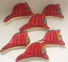 four decorated cookies in the shape of fireman's hats on a white surface