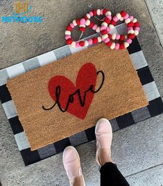 a person standing in front of a door mat with the word love painted on it