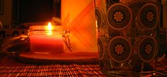 a lit candle sitting on top of a wooden table next to a glass vase filled with water