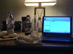 an open laptop computer sitting on top of a counter next to a bottle of water