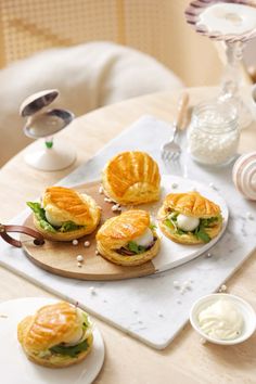 small sandwiches are sitting on a wooden board