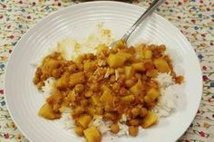 a white plate topped with rice and meat next to a jar of sauce on a table