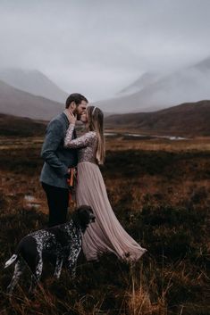 a man and woman standing next to a dog