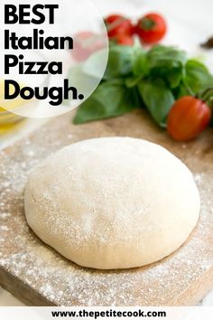 a pizza dough sitting on top of a wooden cutting board next to fresh basil and tomatoes