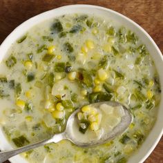 a white bowl filled with corn and broccoli soup on top of a wooden table