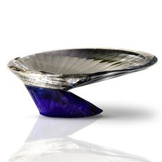 a purple glass bowl sitting on top of a white countertop next to a mirror