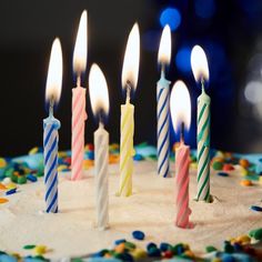 a birthday cake with lit candles on it and sprinkles around the edges